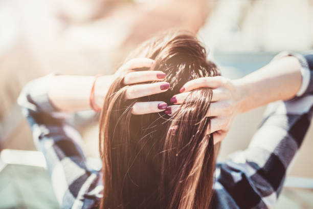 Back view of a brunette beauty coming through her wind swept hair with hands. stock photo