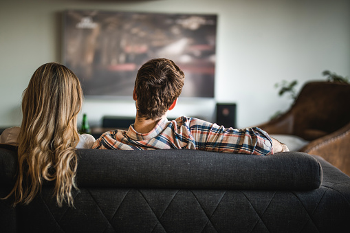 Back View Of A Couple Watching Tv On Sofa At Home Stock 