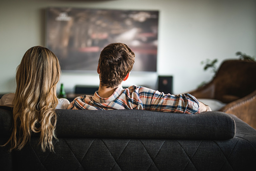 Back View Of A Couple Watching Tv On Sofa At Home Stock Back View Of A Couple Watching Tv On Sofa At Home Stock