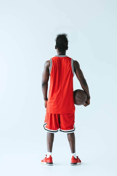 achteraanzicht van afro-amerikaanse basketbalspeler holding bal op grijze achtergrond - basketball player back stockfoto's en -beelden