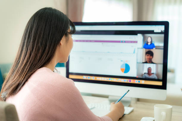 비디오 컨퍼런스에서 계획에 대해 동료들과 이야기하는 아시아 비즈니스 여성의 뒷모습. 화상 통화에서 온라인 회의를 위해 컴퓨터를 사용하는 다민족 비즈니스 팀. 집에서 일하는 사람들의 그 - 일함 뉴스 사진 이미지