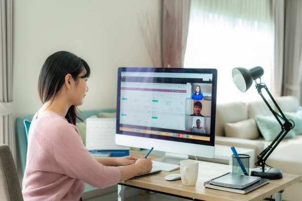 비디오 컨퍼런스에서 계획에 대해 동료들과 이야기하는 아시아 비즈니스 여성의 뒷모습. 화상 통화에서 온라인 회의를 위해 컴퓨터를 사용하는 다민족 비즈니스 팀. 집에서 일하는 사람들의 그 - 재택근무 뉴스 사진 이미지