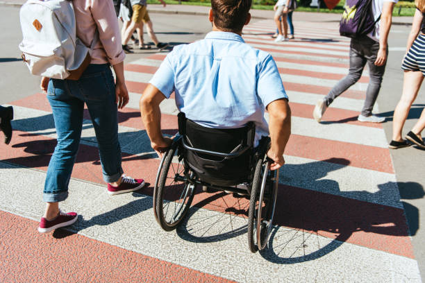 back view of boyfriend in wheelchair and girlfriend crossing crosswalk in city - wheelchair street imagens e fotografias de stock