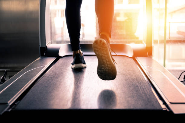 Back view of feet with sneakers of female runner / jogger running on treadmill indoors in action. Back view of feet with sneakers of female runner / jogger running on treadmill indoors in action asian girls feet stock pictures, royalty-free photos & images