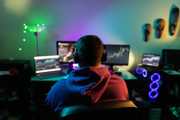 Back view of male gamer while sitting at home and playing games on computer stock photo
