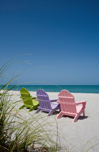 Back View Of Three Pastel Colored Beach Chairs On Sand Stock Photo