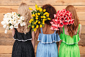 istock Back view of Three women holding bouquets  flowers 1357937169
