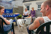 Caucasian family sit chatting in the back garden whilst preparing a barbecue and having family time.