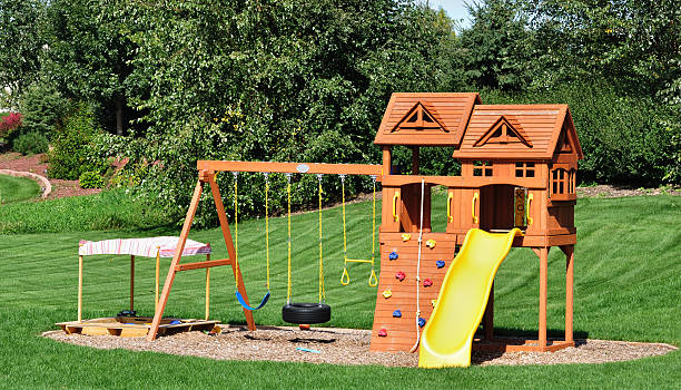 A back yard wooden swing set placed in a garden stock photo