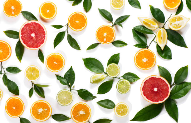Background of citrus fruits Colorful pattern made of slices of citrus fruits (orange, lemon, lime, grapefruit) and green leaves isolated on white background. citrus fruit stock pictures, royalty-free photos & images