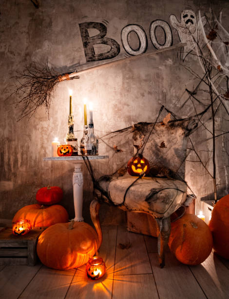 Background of decorations for Halloween celebration. A scary composition with Jack's pumpkin and burning candles, spider webs and a witch's broom on a concrete wall stock photo