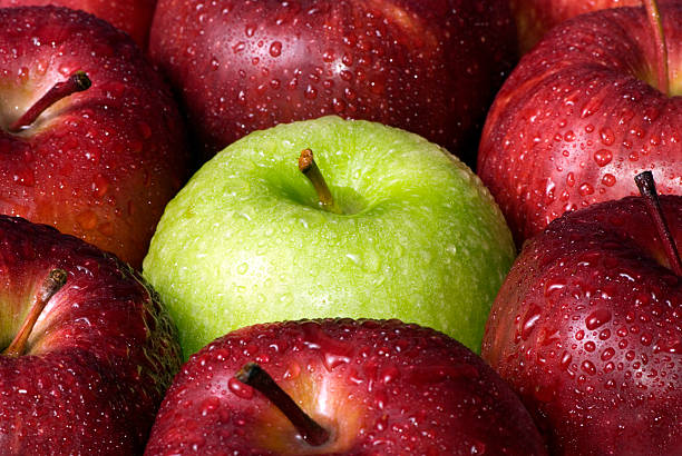 Background of wet red apples with one wet green in middle stock photo