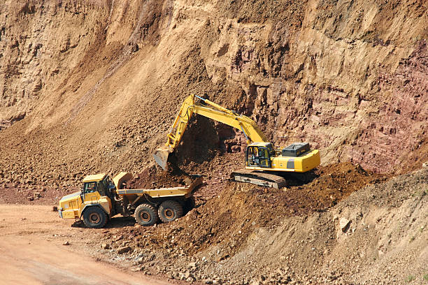 Backhoe and dumptruck at rock quarry stock photo