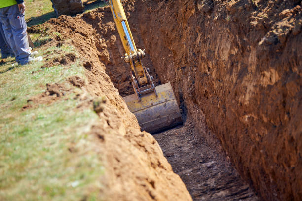 Backhoe - Digging a Trench Excavator digs the foundation for water pipes digging stock pictures, royalty-free photos & images