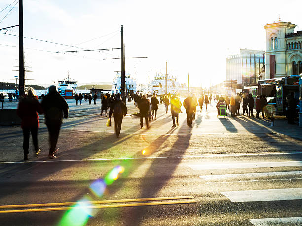Backlit people  walking in the street at sunset. Silhouettes of backlit people  walking  to catch the ferry for Nesodden at sunset .  Aker Brygge, Oslo, Norway. oslo stock pictures, royalty-free photos & images