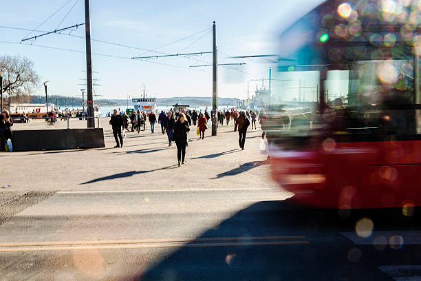 Backlit  red bus and people  walking in the street. Silhouettes of backlit,   blurred  bus with bokeh lights  in the street and  people  walking  to catch the ferry for Nesodden.  Aker Brygge, Oslo, Norway. oslo stock pictures, royalty-free photos & images