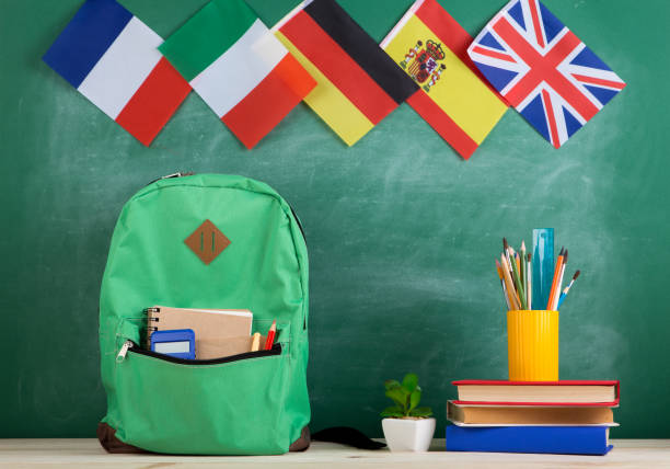 backpack, flags of Spain, France, Great Britain and other countries, books and school supplies of the blackboard stock photo