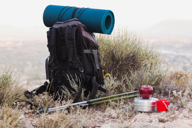 Backpack, hiking poles and food on the mountain stock photo