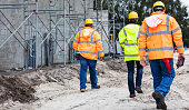 istock Backs of three construction workers walking at job site 1336009709