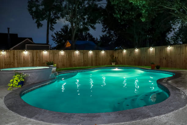 A backyard swimming pool and Hot Tub hot tob at night stock photo