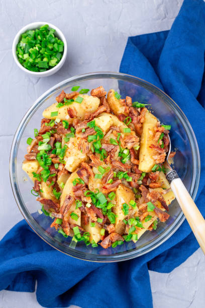 Bacon and onion potato salad dressed with apple cider vinegar and mustard, vertical, top view stock photo