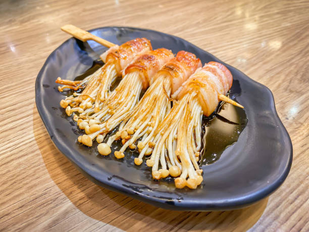 Bacon roll with enoki mushroom grilled with sauce Bacon roll with enoki mushroom grilled with sauce in Japanese style enoki mushroom stock pictures, royalty-free photos & images