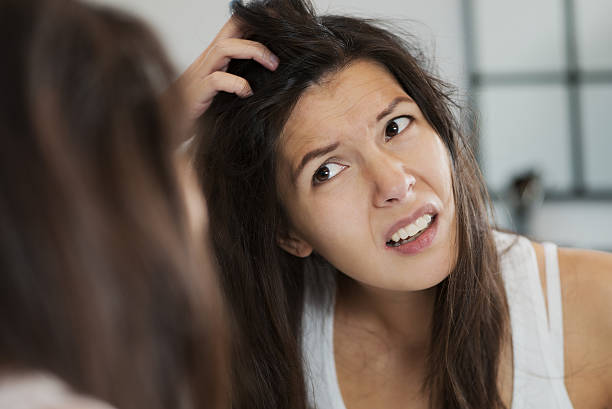 Bad hair day for this woman looking in the mirror Woman having a bad hair day grimacing in disgust as she looks in the mirror and runs her hands through her hair itching hair stock pictures, royalty-free photos & images