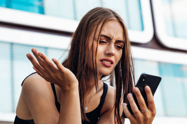 悪いニュース若い女性は、携帯電話でメッセージを読んで - 判らない ストックフォトと画像