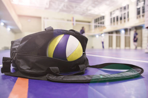 Bag with balls for volleyball lies in the playing hall on the floor, in the background players are warming up. stock photo