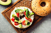 Bagel toast with avocado, cream cheese and tomatoes. Top view