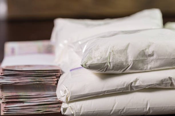 Bags of drugs, and money on table Stash of heroin drugs on table in transparent bags with money in piles heroin stock pictures, royalty-free photos & images