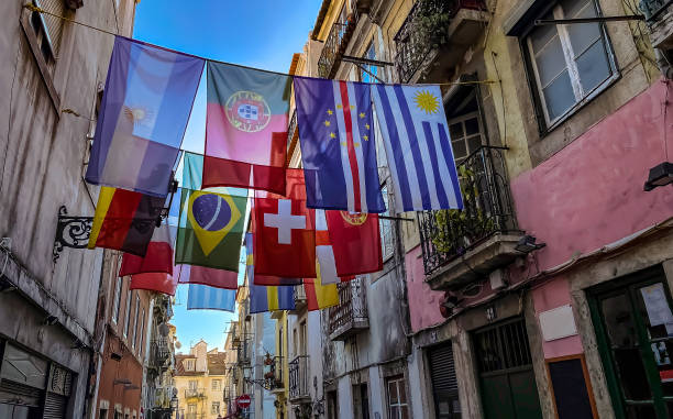 bairro alto. diverse bandiere di diversi paesi sospese tra due edifici in un tipico quartiere di lisbona - correa foto e immagini stock