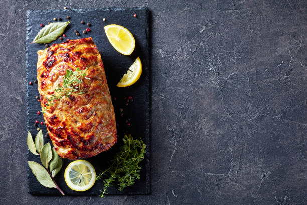 baked chicken meatloaf on a slate tray with lemon slices and fresh thyme on a concrete table, view from above, flat lay, copy space meat loaf stock pictures, royalty-free photos & images