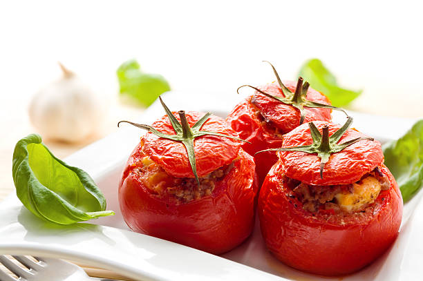 Baked stuffed tomatoes served with fresh basil stock photo
