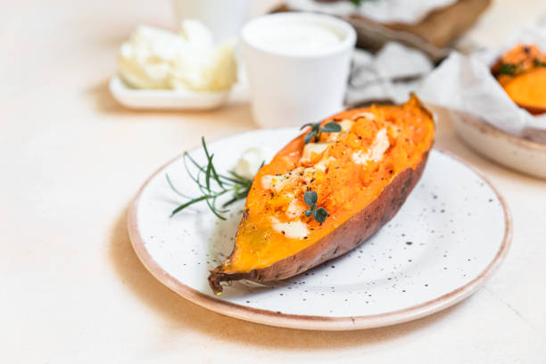 Baked sweet potatoes with mozzarella, herbs and creamy dip on concrete background. stock photo