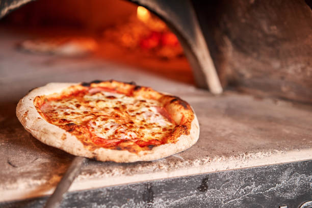 Baked tasty margherita pizza in Traditional wood oven in Naples restaurant, Italy. Original neapolitan pizza. Red hot coal. stock photo