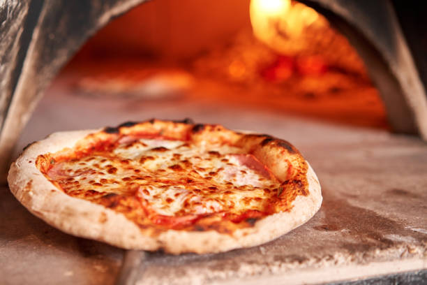 Baked tasty margherita pizza in Traditional wood oven in Naples restaurant, Italy. Original neapolitan pizza. Red hot coal. stock photo