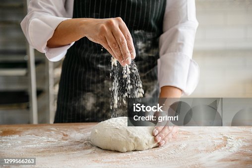 istock A baker dusting flour on a dough to make bread 1299566263