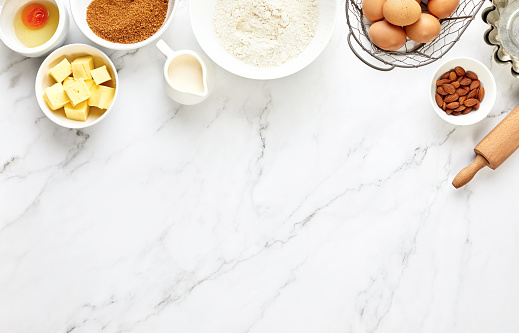 Baking background with ingredients standing on a marble table surface, top down view, blank space for a text