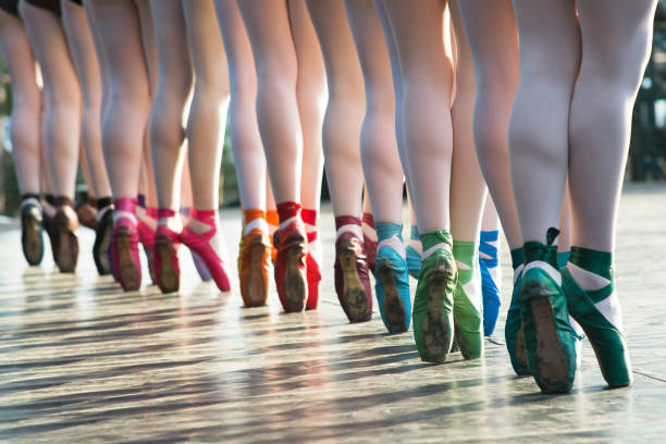 Ballerinas feet dancing on ballet shoes with several colors on stage during a performance. stock photo