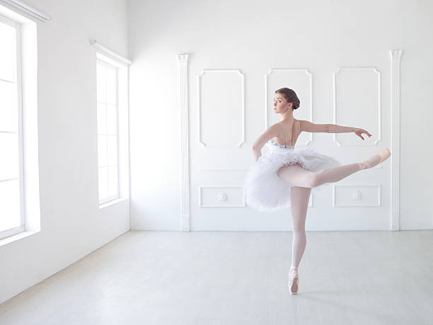 Ballet dancer in white studio Professional ballerina in tutu standing en pointe in attitude pose. Professional make-up and hairstyle. arabesque position stock pictures, royalty-free photos & images