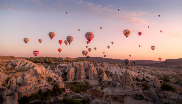 Balloons filled with tourists float at sunrise above the cones of the old village stock photo