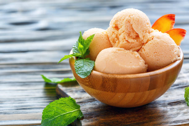 Balls peach ice cream in a wooden bowl. stock photo