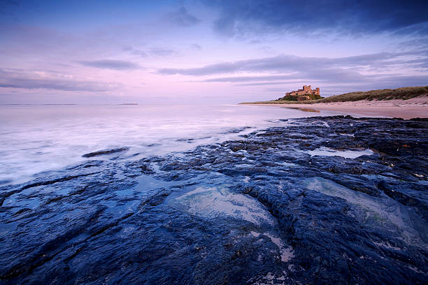 Bamburgh Castle at Sunset This is Bamburgh Castle in Northumberland, England. The Farne Islands are visible on the horizon. northumberland stock pictures, royalty-free photos & images