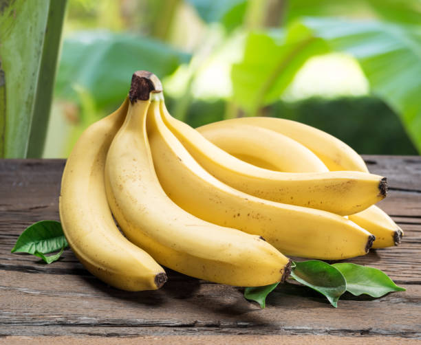 Banana bunch on the wooden table. Banana bunch on the wooden table. Nature at the background. banana stock pictures, royalty-free photos & images