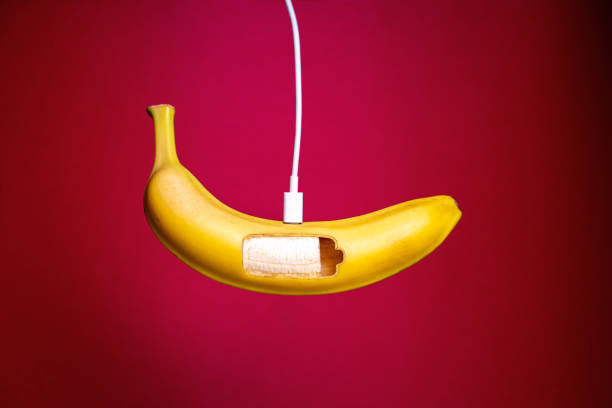 Banana charging on red background. Concept of replenishing energy with nutrients. stock photo
