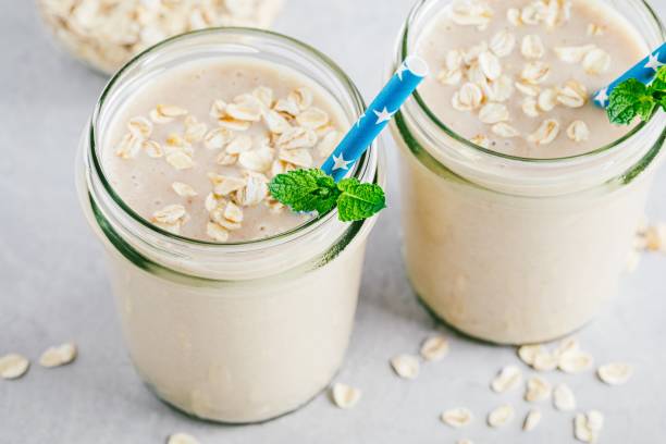 Banana oats smoothie or milkshake in glass mason jars on a stone background stock photo