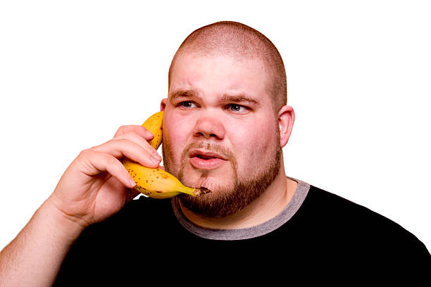 Banana phone Young man chatting on the phone...er, banana. White clipped background. Please rate my images if you like them and I\'d love to hear how they are used! fat man looks at the phone stock pictures, royalty-free photos & images