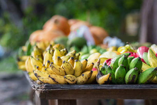 bananen und grüne platanos an einem holztisch im freien auf der hauptstraße von praslin, seychellen - praslin fotos stock-fotos und bilder