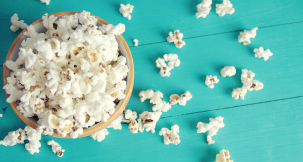 banner for web plate of popcorn on a blue wooden background, top view stock photo
